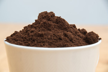 Coffee grounds in a white cup on  a wooden table for breakfast
