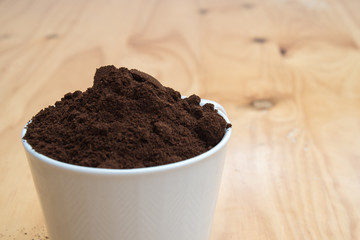 Coffee grounds in a white cup on  a wooden table for breakfast