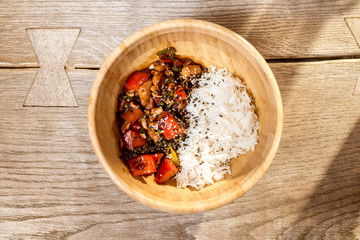 Asian wok rise meal served in the wooden plate on the table