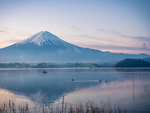 sunrise landscape view from kawaguchi lake with motion blur from group of duck foreground and fuji mountain background with fog from japan