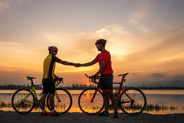 Two cyclists shaking hand after finish ride bicycle together