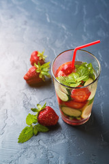 Detox water with strawberry and cucumber in a glass on dark background. Selective focus.
