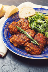 Platter of chicken thighs piri piri coated in hot sauce with salad.