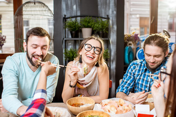 Young friends having fun during the dinner with asian food sitting at the modern restaurant