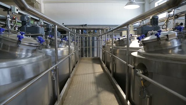 Production tanks, storages at dairy. Huge tanks for storing and fermenting milk at a dairy factory. Pipeline at dairy factory. Panoramic shooting. Equipment at dairy plant.