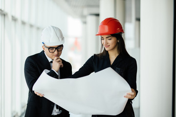 Businessman architects look at paper plan business woman architect in office to discuss business projects near panoramic window.