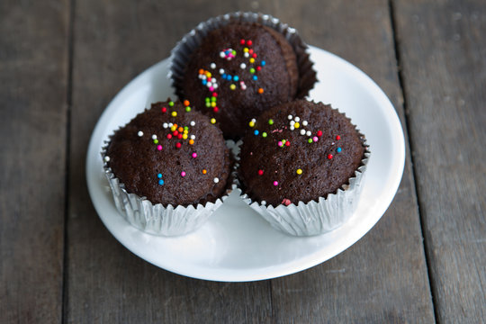 Chocolate cakes with topping several color on white dish.