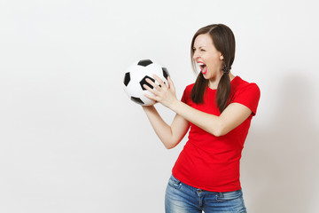 European young crazy angry screaming woman, two fun pony tails, football fan or player in red uniform holding soccer ball isolated on white background. Sport play football, healthy lifestyle concept.
