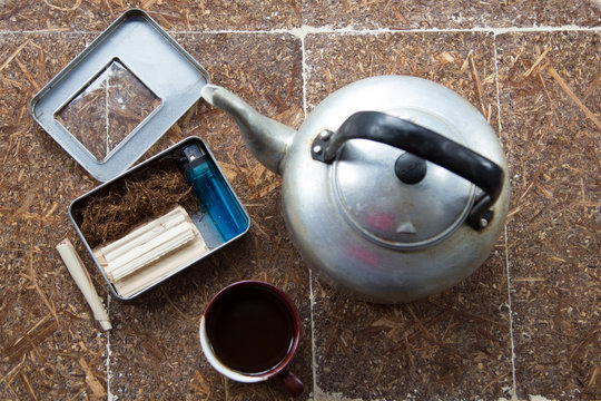 The lighter, coffee cup, tobacco and old pot put on the wood table.