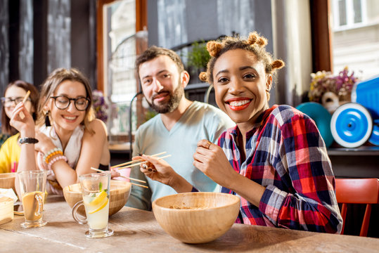 Young friends having fun during the dinner with asian food sitting at the modern restaurant