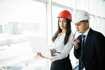 Engineering and architecture concept. Engineers working on a building site holding laptop, architect man working with engineer woman inspection in workplace for architectural plan