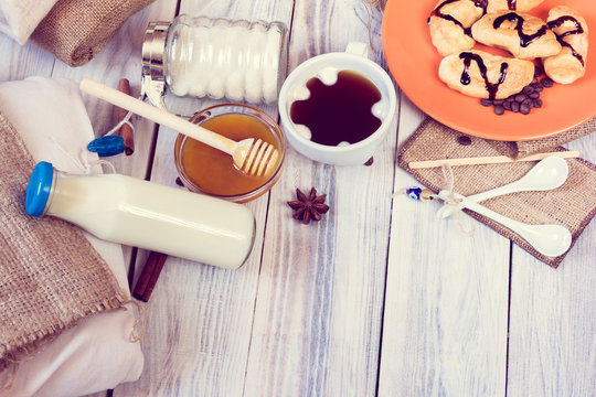 Breakfast of coffee, croissants, milk, honey, sugar, cinnamon, anise