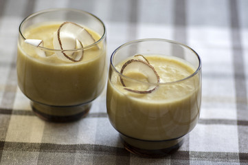 Pineapple smoothie with bananas, oatmeals and coconut milk, decorated with coconut chips, checkered tablecloth