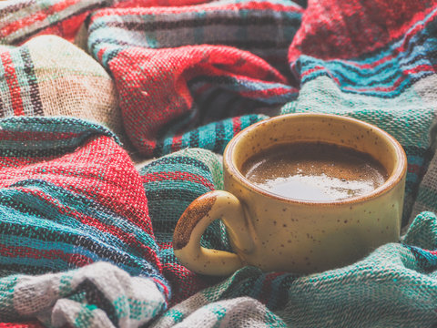 A Cup of coffee and colored textiles. Comfort on cold days. Home comfort.
