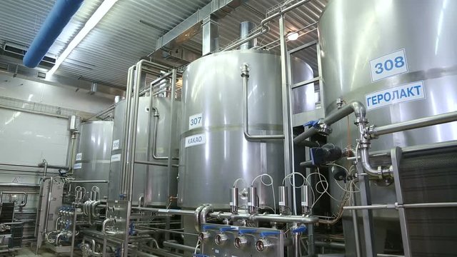 Production tanks, storages at dairy. Pipeline at dairy factory. Huge tanks for storing and fermenting milk at a dairy factory. Panoramic shooting.