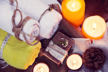 Fototapeta na wymiar SPA consist from towels, candles, soap, flowers, and fir cone