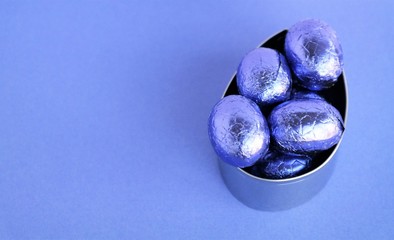 purple Easter chocolate eggs in metal shape, Passover background with copy space 