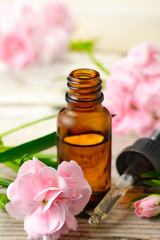 Obraz na płótnie Canvas Carnation absolute essential oil and pink flowers on the wooden table