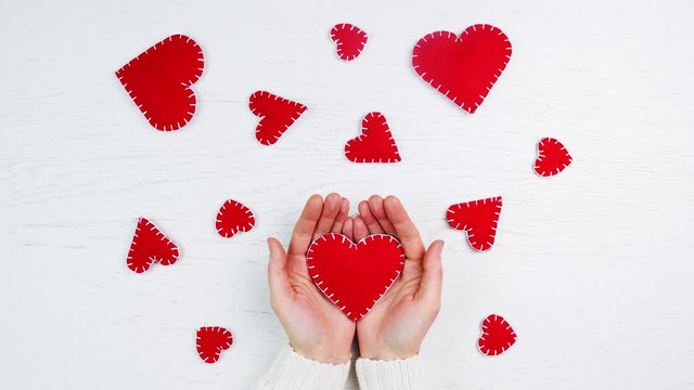 female hands with red hearts valentines on white background - animation, stop motion
