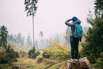 Young Woman Standing On Stump In Forest And Looking Into Distanc