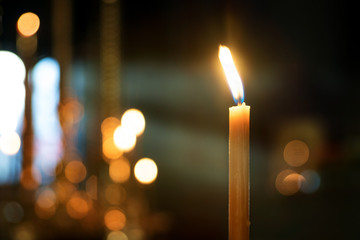 candle in the Church on a blurred background of candles and rays from the window