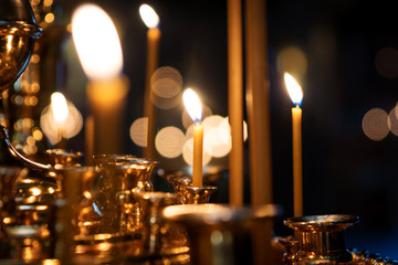 burning candles in a Church on a dark background with blurred bokeh of the candles