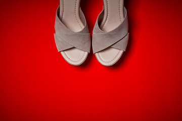 Top view of female beige shoes on an intense red background