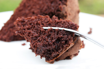 Closeup sliced chocolate cake with fork. Sweet dessert.