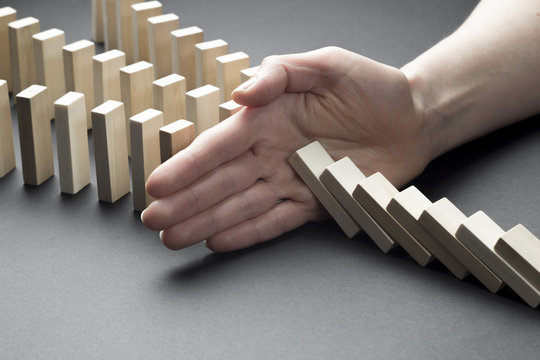 The financial crisis and economic decline. Businessman hand stop domino continuous tipping or risk. 