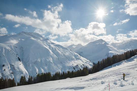 Snowboarder riding down the slope on beautiful sunny winter day in Sedrun ski resort