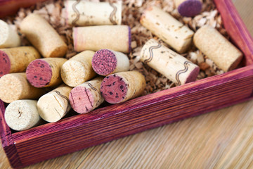 Used corks close up in red wooden box. Old corks from red and white wine on natural wood. Copy space. Soft focus.