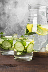 Detox drink with cucumber, lemon and mint in glasses on a wooden background