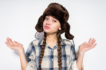funny young Russian girl in a warm cap with ear-flaps waving her hands