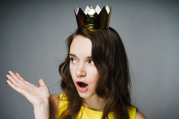lovely surprised girl with a golden crown on her head asks a question