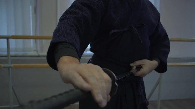 Close-up, The Samurai's Hands Slowly Insert into the Katana's Sword Leaf