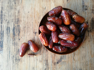 Dates in a wooden plate on a wooden table