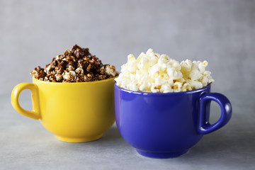 Popcorn in yellow and blue bowls on a gray background.