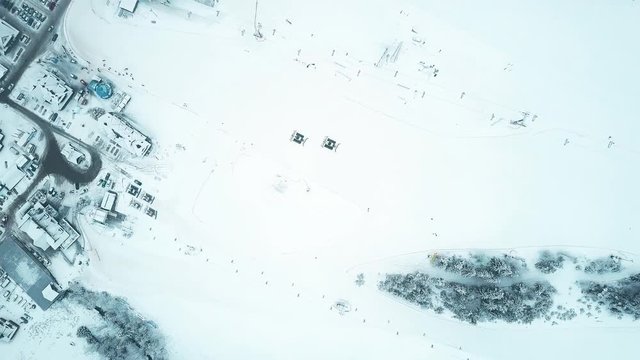 Aerial top down view of two snowcats or snow groomers on a mountain ski slope