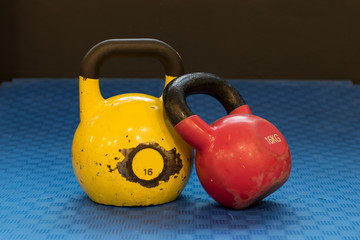 Naklejka na ściany i meble Red and yellow used and old kettlebells on a blue background. Workout equipment