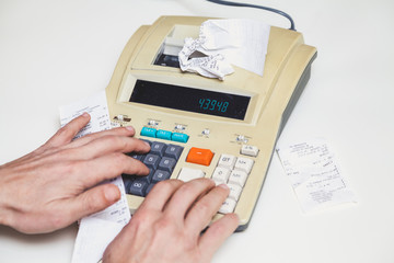 hand presses keys on printing calculator beside lie checks