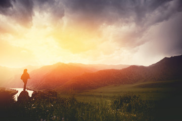 Traveling woman with backpack looking river and mountains, sunny day. silhouette