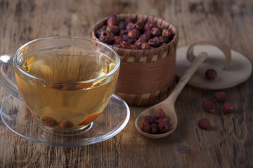 In a glass cup   tea of rosehip   on an old wooden table