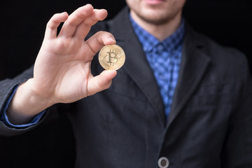 young businessman holds a gold coin bitcoin