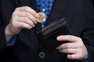 a young businessman puts in a coin purse a crypto currency bitcoin