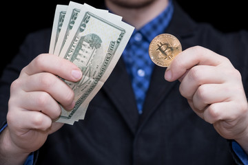 young businessman holding dollars and coins of crypto currency bitcoin
