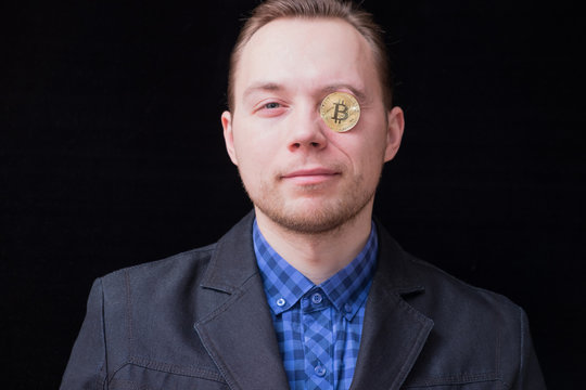 young businessman holds an eye with a gold coin bitkoin