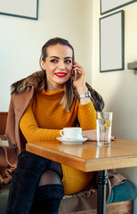 woman in a cafe drink coffee and speaking on smartphone .