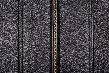 The surface texture is made of genuine black leather with two seams with a double stitch and a zipper in the center. Close-up.