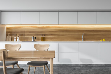 Front view of a white and wooden kitchen, table
