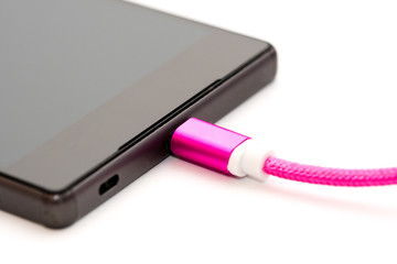 Black smartphone charging. Pink micro usb cable pluged in mobile phone. Isolated on white background.